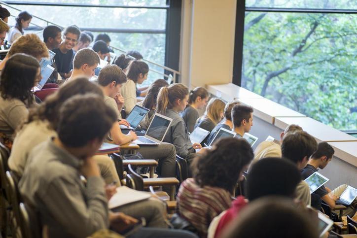 étudiants recevant une copie d'un professeur dans un amphithéâtre